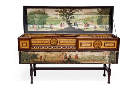 A wide shot of a virginal - an old keyboard instrument. It is large and rectangular with short legs and ornate panelling