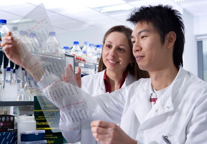 2 students in white lab coats examining experimental results in a research lab