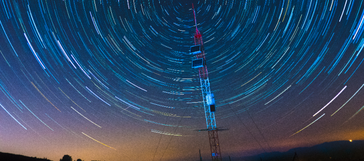 A satellite communications tower under the stars at night
