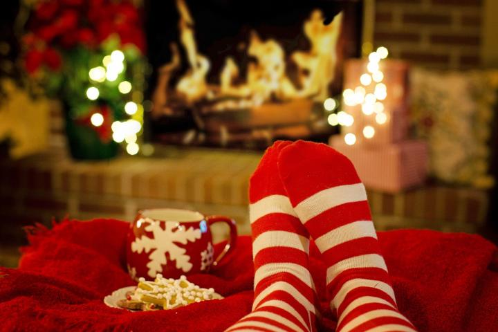 Photograph of a person's feet in cosy socks sitting in front of a festive fireplace