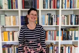 Hannah Holtschneider standing in front of bookshelves
