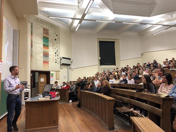An academic teaching a lecture theatre of students.