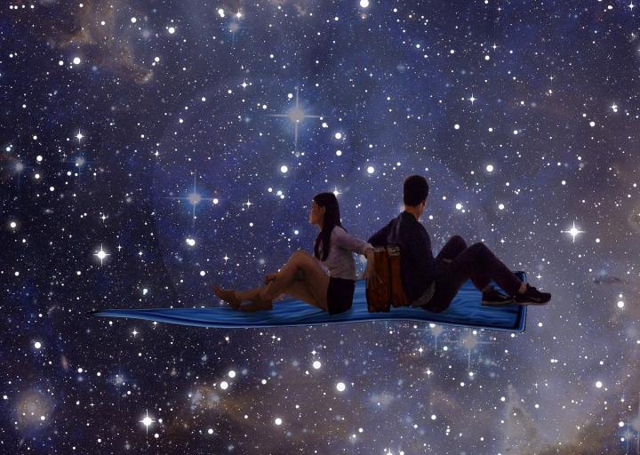 Image of a magic carpet flying with two people sitting on it, looking at a dark night sky and the stars.