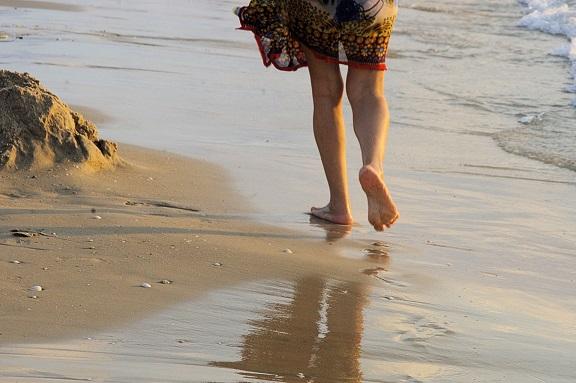 Photograph of someone walking along the beach, leaving footprints in the sand. 
