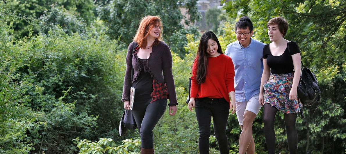 Four students walking through George Square Gardens