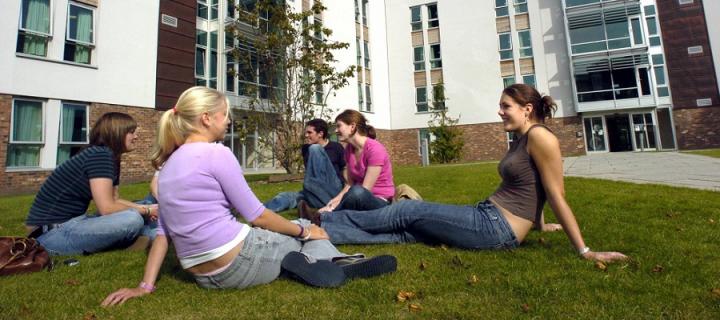 Students relaxing on the grass in front of student accommodation