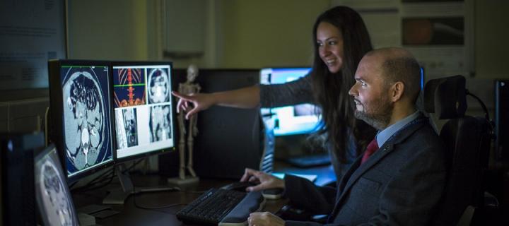 Two people looking at the human brain on two computer screens