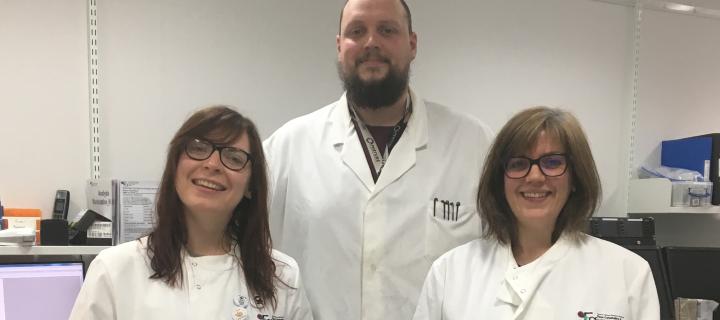 Mari George, Will Ramsay, and Shonna Johnston wearing lab coats, smiling in a lab