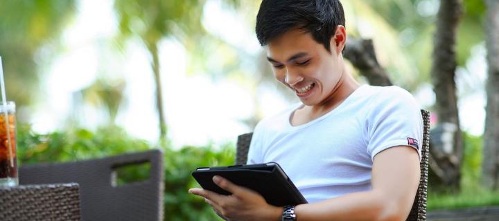 man sitting on bench smiling using tablet