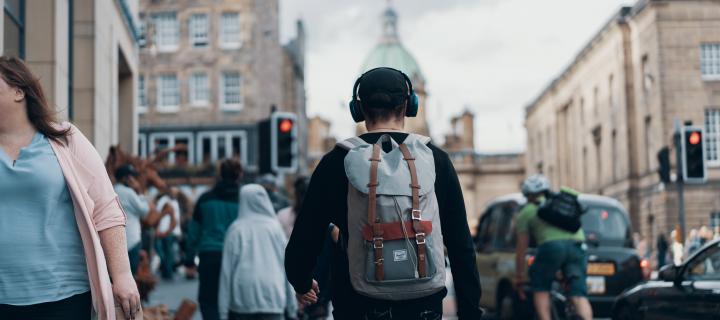 Man with headphones on walking down Edinburgh's High Street