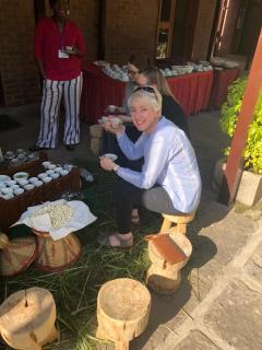 Dr Kellie Watson sitting on a wooden stool while having a beverage during a work break in Ethiopia.
