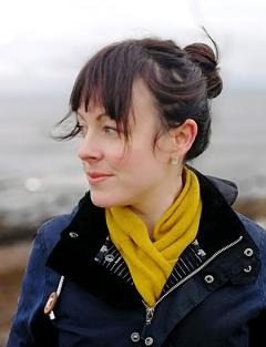 Head and shoulders shot of Dr Laura Mair in warm outdoor clothes with the sea behind