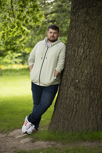Kevin leans against a tree in George Square gardens