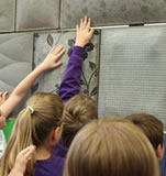 School pupils touch the fabric formed concrete wall