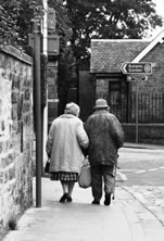 Elderly couple walking arm-in-arm on a street in Edinburgh