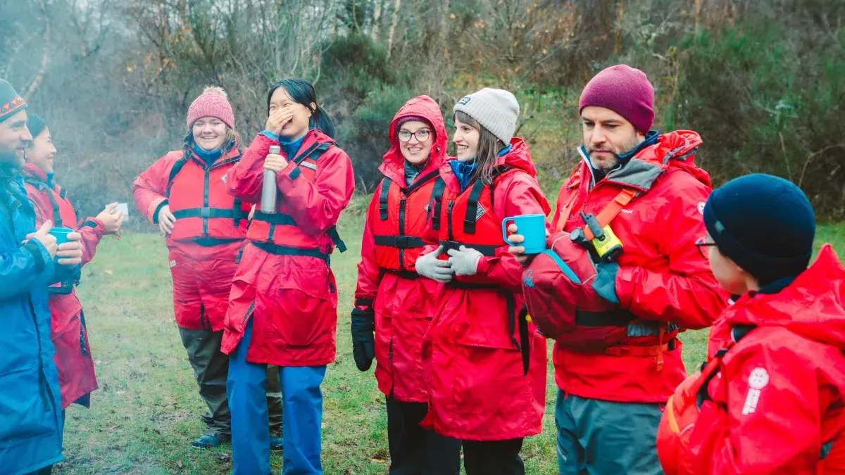 A group or students and staff, wearing red jackets, attending a nature-based learning course at Firbush, the University of Edinburgh's outdoor education centre in Perthshire
