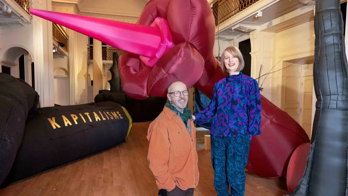 Two artists pose with their work in the Talbot Rice Gallery