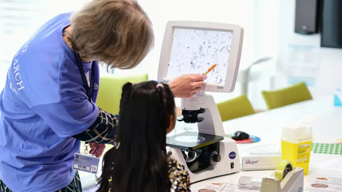 A university researcher shows a child research modelling at the Institute for Genetics and Cancer