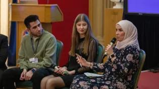 Three people in conversation during a panel discussion about Education Beyond Borders