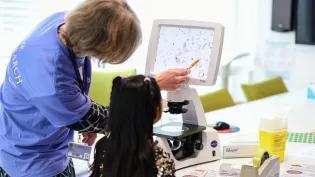 A university researcher shows a child research modelling at the Institute for Genetics and Cancer