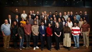 36 cohort members standing and looking to camera 