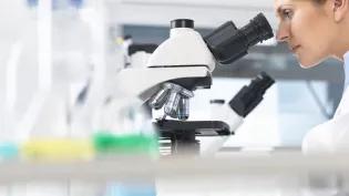 A female scientist looking through a microscope