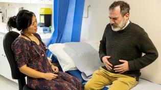 Male patient with stomach pain talking to female doctor