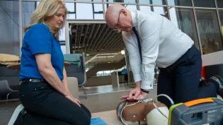 First Minister of Scotland John Swinney performs CPR on a model, assisted by Susan Gardner from Save a Life for Scotland