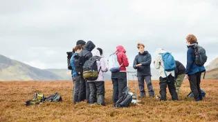 group of students standing in an open feild in windy conditions