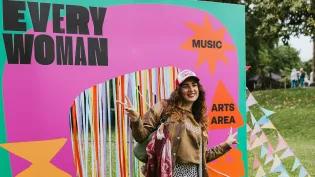 A woman wearing a cap stood in front of a banner displaying the "Everywoman" logo in pink and green.