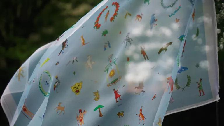 A textile flag featuring emblems from 60 countries blows in the wind. 