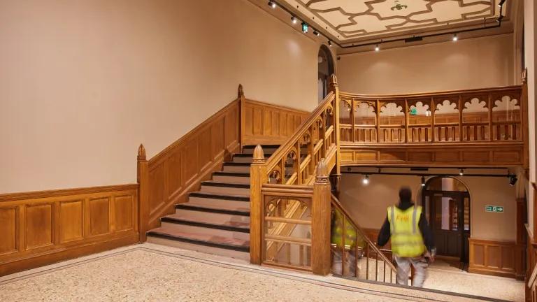 An interior image of the main staircase featuring a construction worker during the renovation. 