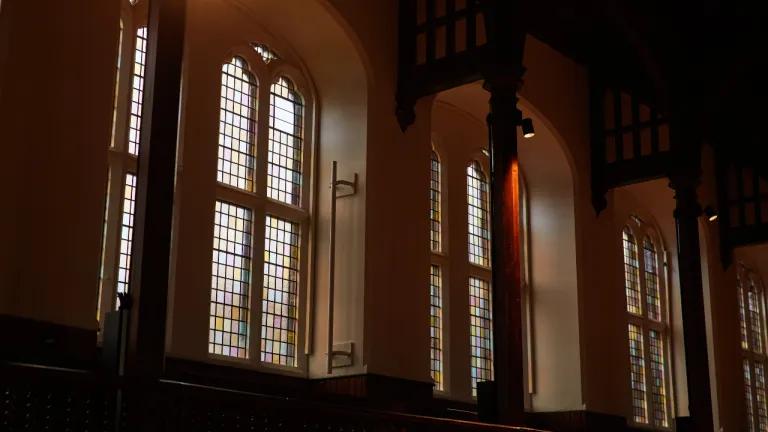 Original stained-glass windows with light shining through them into the interior.