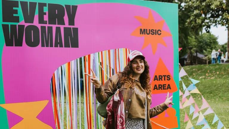 A woman wearing a cap stood in front of a banner displaying the "Everywoman" logo in pink and green.