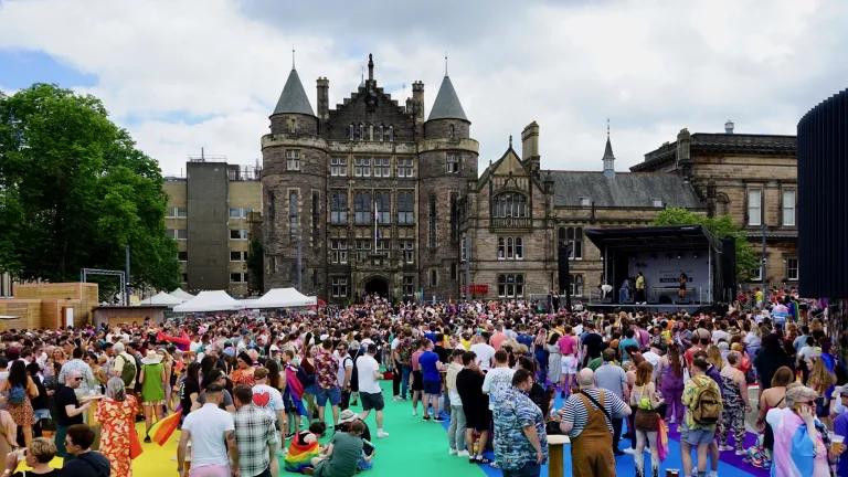 Crowds at Edinburgh Pride Festival Village on Bristo Square with Teviot Row House in the background. Image taken during Pride Edinburgh 2019.