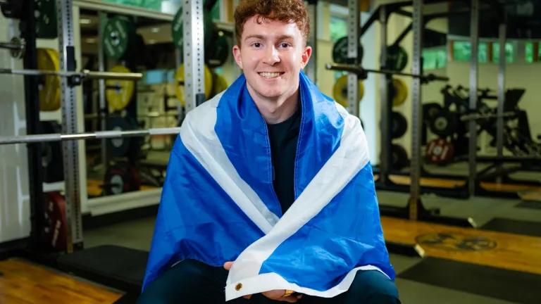 Archie Goodburn draped in a Scottish flag photographed in the University performance gym. 