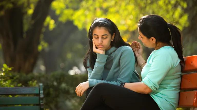 Mother comforting daughter at on park bench