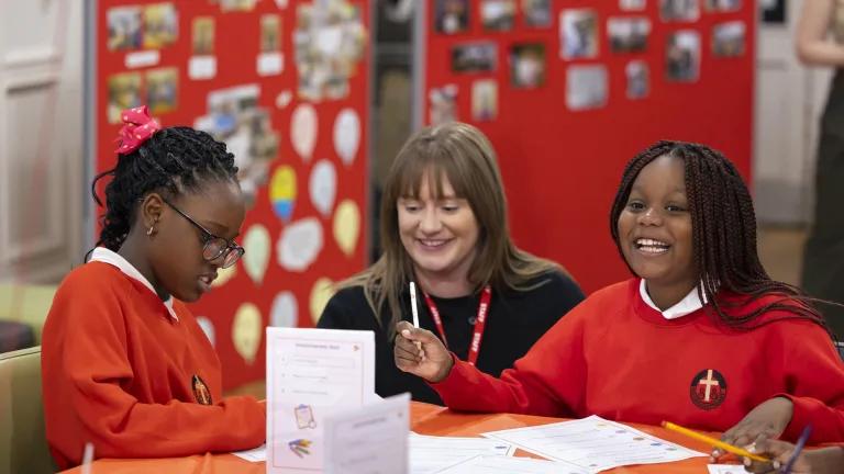 Two School pupils sat at a classroom table with Kim Rowson, IntoUniversity Scotland Operations Manager 