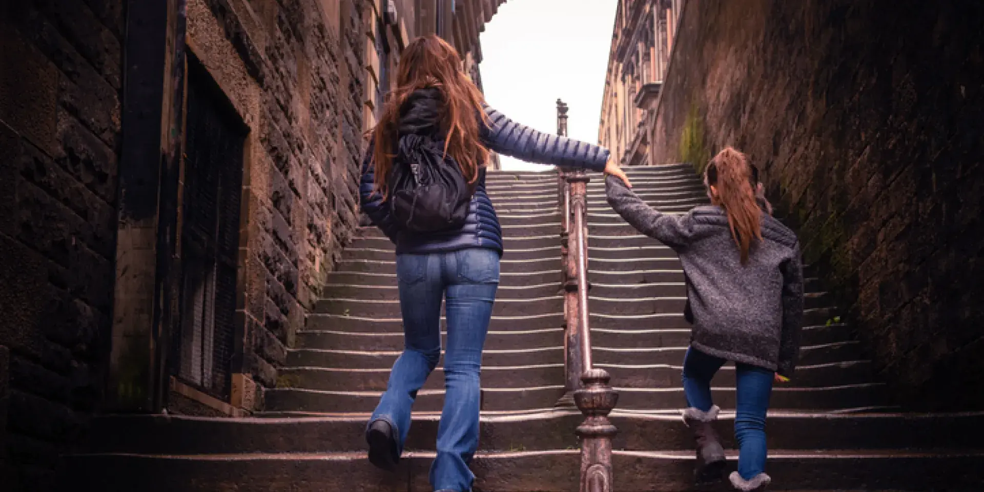 Mother holding a child's hands climbing a staircase