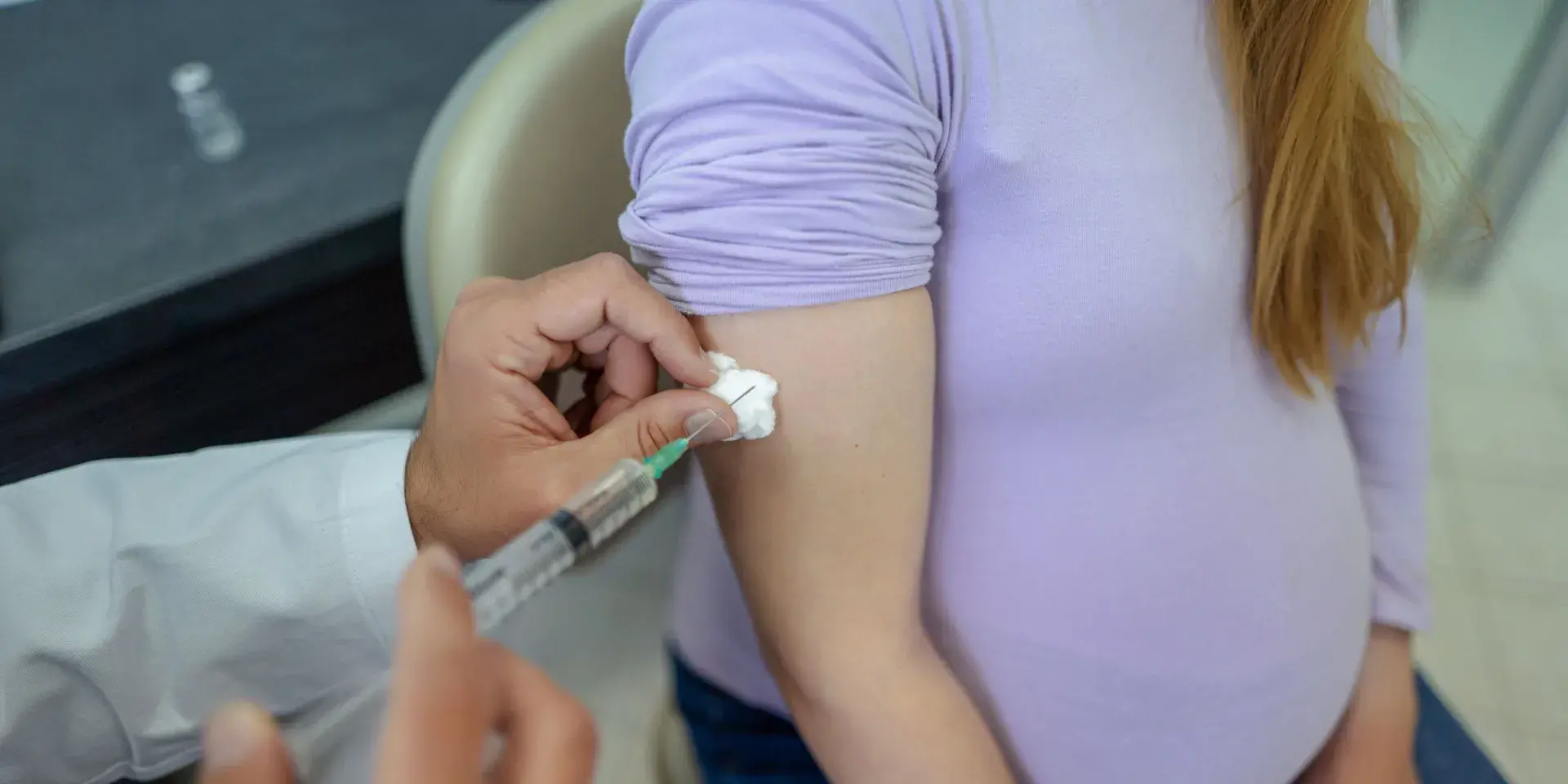 A pregnant woman receives a vaccine from a doctor