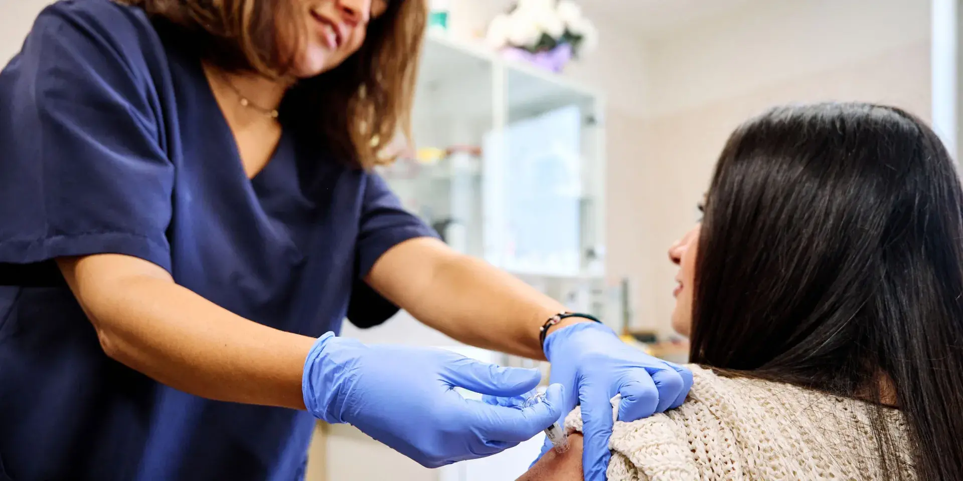 Young woman receiving a vaccination from a nurse