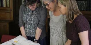 Group of three people looking at a historic book