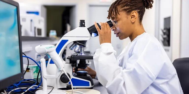 Female scientist looking through a microscope in a laboratory