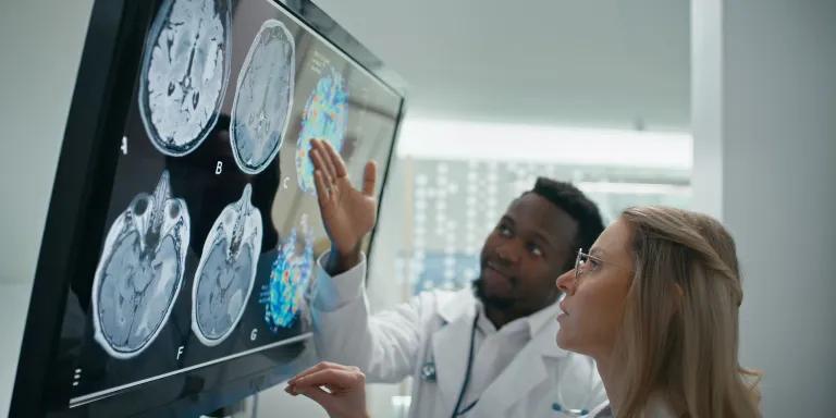 Two doctors look at images on a screen of brain scans
