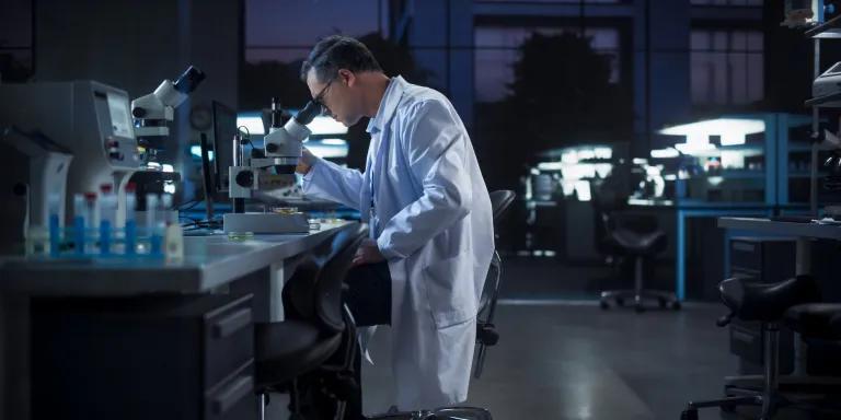 A scientist looking at a DNA sample under a microscope in a laboratory