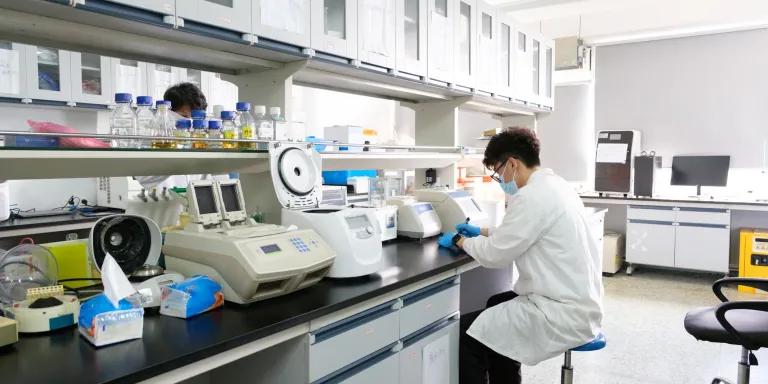 A scientist in a white coat working in a lab