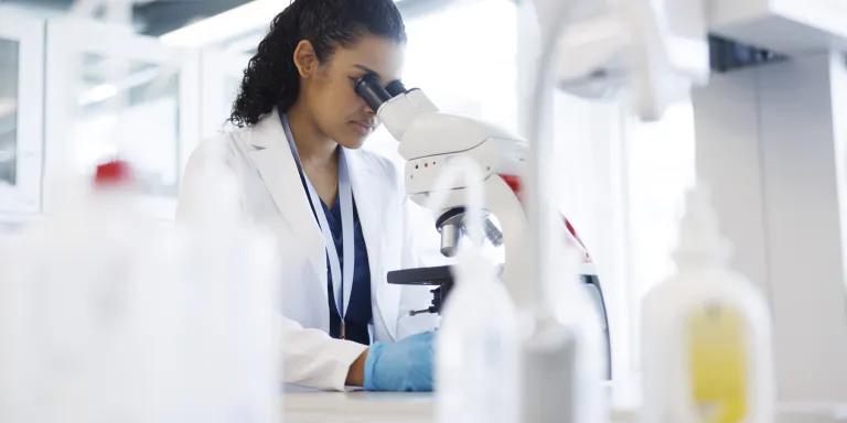 A female scientist looking through a microscope in a laboratory