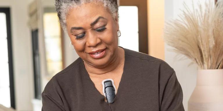 Close up of an older woman with a small, black heart monitor attached to her chest