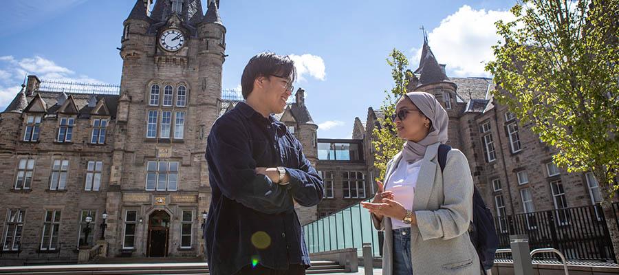 Two students standing chatting outside the Edinburgh Futures Institute building