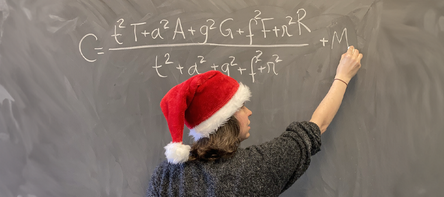 Dr Ana Rita Pires writes the perfect Christmas formula on a chalkboard. She is wearing a santa hat.